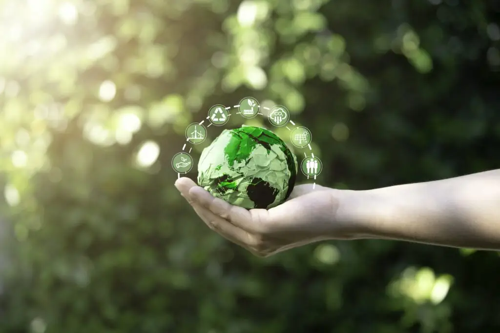 Businessman holding green scrap paper ball with world map and environment icon